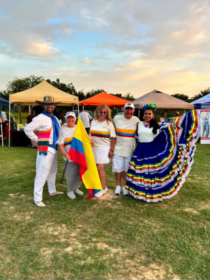 Grupo de ColombiArte con la bandera de Colombia y polleras en un festival al aire libre