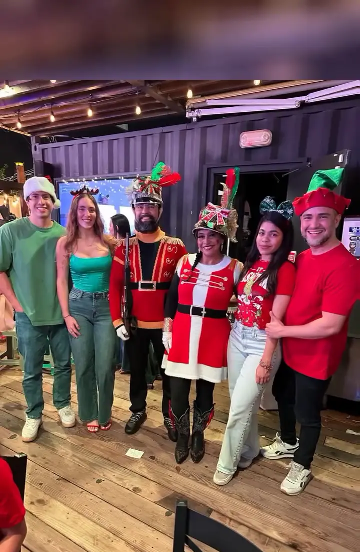 ColombiArte con trajes navideños posando con invitados en una celebración navideña
