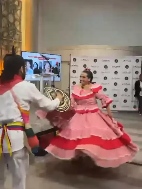 Pareja de ColombiArte bailando: él con sombrero vueltiao en la mano y ella con pollera rosada en pleno giro