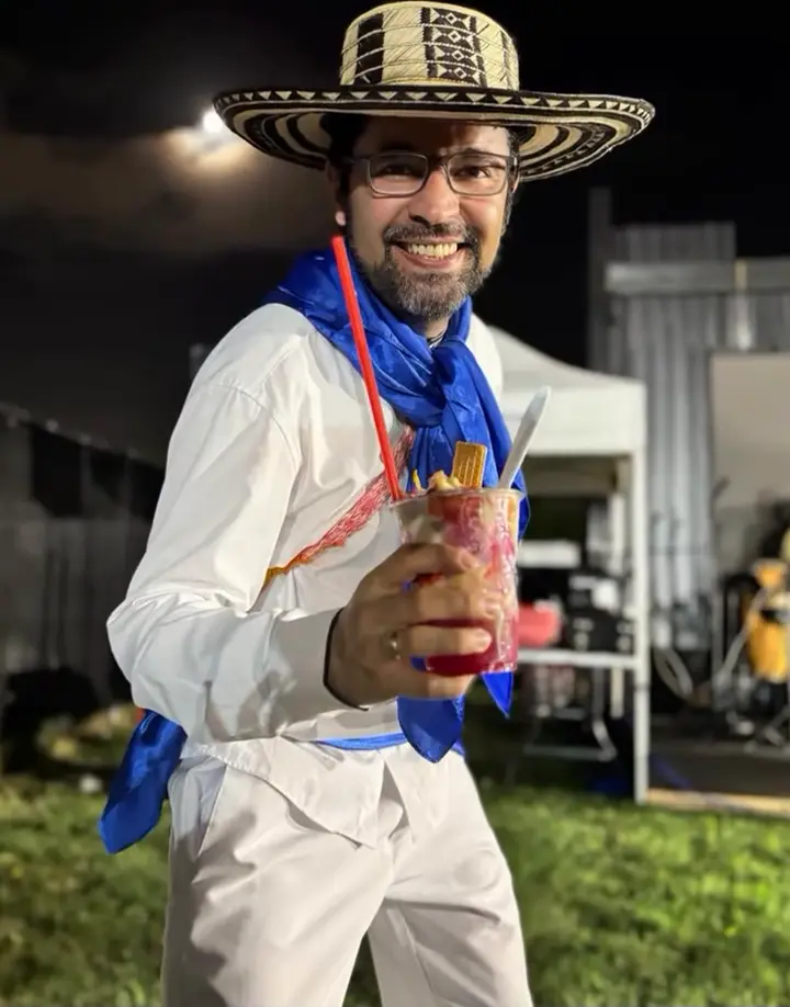 Bailarín sonriente con sombrero vueltiao y pañuelo azul en una celebración nocturna